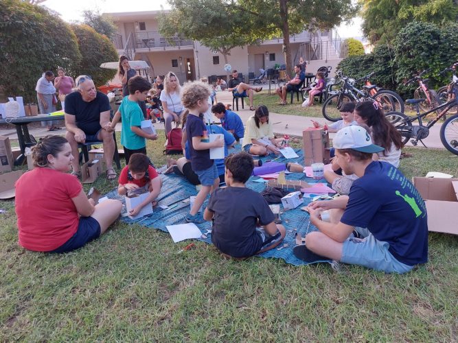 אנשים וילדים יושבים על הדשא